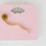 Top view of floor scales for weight control and measuring tape for controlling body shapes on white background