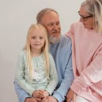 Grandparents lovingly embrace their granddaughter in a bright, studio setting, capturing family warmth and connection.