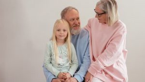 Grandparents lovingly embrace their granddaughter in a bright, studio setting, capturing family warmth and connection.